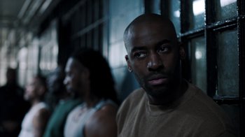 Movie still from “The Night Of” (2016), directed by James Marsh – A man in a tan shirt is looking at the camera; Close Up shot, Over the shoulder angle