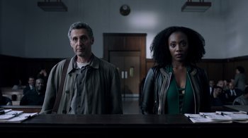Movie still from “The Night Of” (2016), directed by James Marsh – A man and a woman standing next to each other in a room; Medium shot, Low angle
