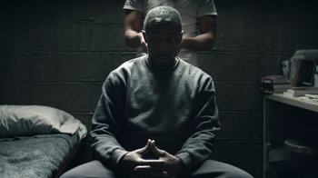 Movie still from “The Night Of” (2016), directed by James Marsh – A man sitting in a room next to another man; Medium shot, Over the shoulder angle