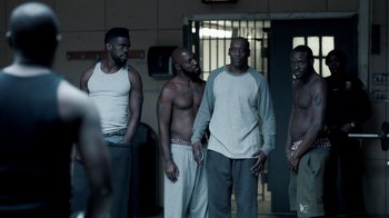 Movie still from “The Night Of” (2016), directed by James Marsh – A group of men standing next to each other in a room; Medium shot, Over the shoulder angle