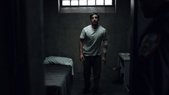 Movie still from “The Night Of” (2016), directed by James Marsh – A man standing in a dark room next to a bed; Medium shot, Low angle