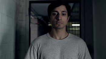 Movie still from “The Night Of” (2016), directed by James Marsh – A man in a gray t - shirt is looking at the camera; Close Up shot, Over the shoulder angle