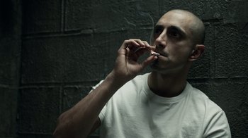 Movie still from “The Night Of” (2016), directed by James Marsh – A man smoking a cigarette in front of a brick wall; Close Up shot, Low angle