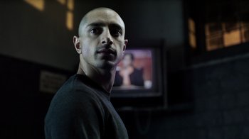 Movie still from “The Night Of” (2016), directed by James Marsh – A man standing in front of a tv in a room; Close Up shot, Low angle