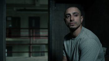 Movie still from “The Night Of” (2016), directed by James Marsh – A man in a gray shirt is posing for a picture; Close Up shot, Over the shoulder angle