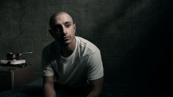 Movie still from “The Night Of” (2016), directed by James Marsh – A man with a shaved head sitting in a room; Close Up shot, High angle