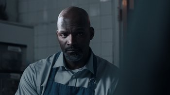 Movie still from “The Night Of” (2016), directed by James Marsh – A man with a beard wearing an apron; Close Up shot, Over the shoulder angle