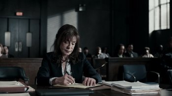 Movie still from “The Night Of” (2016), directed by James Marsh – A woman sitting at a table writing on a piece of paper; Medium shot, High angle