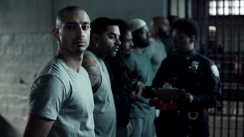 Movie still from “The Night Of” (2016), directed by James Marsh – A group of men standing next to each other in a room; Medium shot, High angle