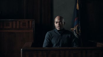 Movie still from “The Night Of” (2016), directed by James Marsh – A man sitting in front of a judge in a courtroom; Medium shot, Over the shoulder angle