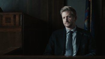 Movie still from “The Night Of” (2016), directed by James Marsh – A man in a suit and tie sitting at a table; Close Up shot, Over the shoulder angle
