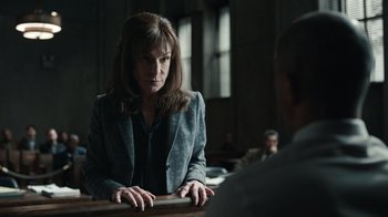 Movie still from “The Night Of” (2016), directed by James Marsh – A woman in a suit is sitting at a table; Medium shot, Over the shoulder angle