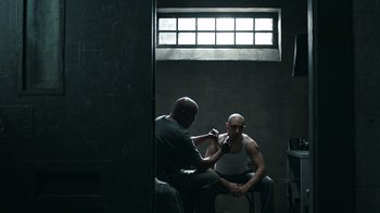 Movie still from “The Night Of” (2016), directed by James Marsh – Two men sitting next to each other in a dark room; Wide shot, Over the shoulder angle