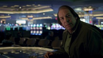 Movie still from “The Night Of” (2016), directed by James Marsh – A man sitting at a table in front of a bar; Close Up shot, Low angle