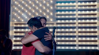 Movie still from “The Normal Heart” (2014), directed by Ryan Murphy – Two people hugging in front of a microphone; Medium shot, Over the shoulder angle