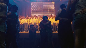 Movie still from “The Normal Heart” (2014), directed by Ryan Murphy – A group of people standing in front of an american flag; Wide shot, Over the shoulder angle