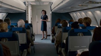 Movie still from “The Normal Heart” (2014), directed by Ryan Murphy – An airline stewardess stands on the aisle of an airplane; Wide shot, High angle