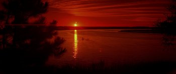 Movie still from “The Notebook” (2004), directed by Nick Cassavetes – A person in a canoe on a body of water at sunset; Extreme Wide shot, High angle