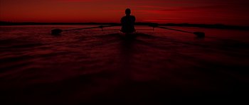 Movie still from “The Notebook” (2004), directed by Nick Cassavetes – A person sitting in a boat on a body of water at sunset; Extreme Wide shot, Low angle