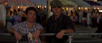 Movie still from “The Notebook” (2004), directed by Nick Cassavetes – Two young men sitting next to each other at a fair; Medium shot, Low angle