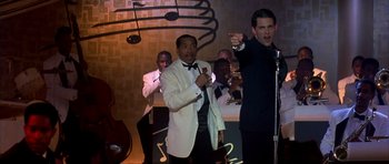 Movie still from “The Notebook” (2004), directed by Nick Cassavetes – Two men in tuxedos singing into microphones in front of a crowd; Medium shot, Low angle