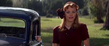 Movie still from “The Notebook” (2004), directed by Nick Cassavetes – A beautiful young woman wearing a hat standing in front of an antique car; Close Up shot, Over the shoulder angle