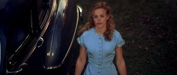 Movie still from “The Notebook” (2004), directed by Nick Cassavetes – A woman standing next to a car in a blue dress; Medium shot, High angle