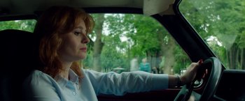 Movie still from “The November Man” (2014), directed by Roger Donaldson – A woman sitting in the passenger seat of a car looking out the window; Close Up shot, Low angle