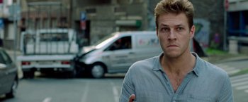 Movie still from “The November Man” (2014), directed by Roger Donaldson – A man standing in front of a van on the street; Close Up shot, Over the shoulder angle