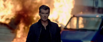 Movie still from “The November Man” (2014), directed by Roger Donaldson – Pierce brosnan in front of an exploding car; Medium shot, Over the shoulder angle