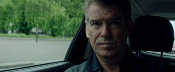 Movie still from “The November Man” (2014), directed by Roger Donaldson – A person in a car with trees in the background; Close Up shot, Over the shoulder angle