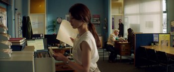 Movie still from “The November Man” (2014), directed by Roger Donaldson – A woman standing in front of a desk holding papers; Medium shot, Over the shoulder angle