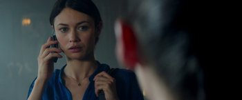 Movie still from “The November Man” (2014), directed by Roger Donaldson – A woman looking into a mirror while holding a red object in her hand; Close Up shot, Over the shoulder angle