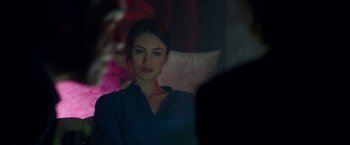 Movie still from “The November Man” (2014), directed by Roger Donaldson – A beautiful young woman sitting in a chair; Close Up shot, Over the shoulder angle