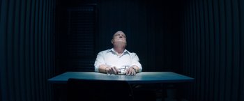 Movie still from “The November Man” (2014), directed by Roger Donaldson – A man sitting at a table with his eyes closed; Medium shot, Low angle