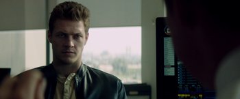 Movie still from “The November Man” (2014), directed by Roger Donaldson – A man in a leather jacket and a tie in front of a window; Close Up shot, Over the shoulder angle