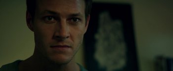 Movie still from “The November Man” (2014), directed by Roger Donaldson – A man's face in a dark room; Close Up shot, Over the shoulder angle