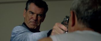 Movie still from “The November Man” (2014), directed by Roger Donaldson – A man holding a gun while looking at another man; Close Up shot, Over the shoulder angle
