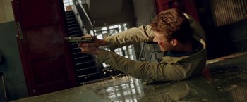 Movie still from “The November Man” (2014), directed by Roger Donaldson – A man holding a gun while laying on the ground; Medium shot, Low angle