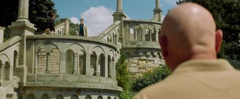 Movie still from “The November Man” (2014), directed by Roger Donaldson – A man standing on top of a stone building; Extreme Wide shot, Low angle