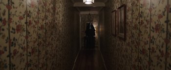 Movie still from “The Nun” (2018), directed by Corin Hardy – A woman dressed as a nun in a dark hallway; Wide shot, Over the shoulder angle