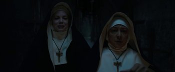 Movie still from “The Nun” (2018), directed by Corin Hardy – Two women dressed as nuns in a dark room; Medium shot, Low angle