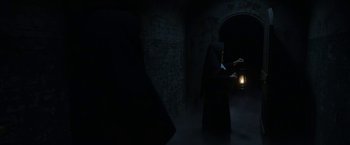Movie still from “The Nun” (2018), directed by Corin Hardy – An old woman in a dark room with a candle; Wide shot, Low angle