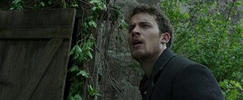 Movie still from “The Nun” (2018), directed by Corin Hardy – A man standing in front of a tree looking up at the sky; Close Up shot, Low angle
