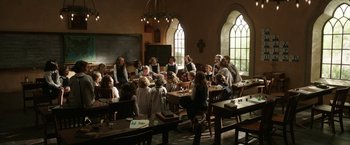 Movie still from “The Nun” (2018), directed by Corin Hardy – A group of people sitting at a table in front of a window; Wide shot, High angle