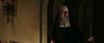 Movie still from “The Nun” (2018), directed by Corin Hardy – A woman dressed as a nun standing in front of an archway; Medium shot, Low angle