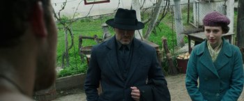 Movie still from “The Nun” (2018), directed by Corin Hardy – A man in a suit and hat standing in a yard; Medium shot, Over the shoulder angle