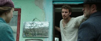 Movie still from “The Nun” (2018), directed by Corin Hardy – A man standing in front of an open door; Close Up shot, Low angle