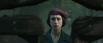 Movie still from “The Nun” (2018), directed by Corin Hardy – A young woman wearing a purple hat and a green coat; Close Up shot, Over the shoulder angle