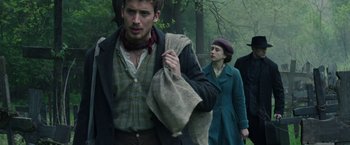 Movie still from “The Nun” (2018), directed by Corin Hardy – A group of people walking through a forest; Medium shot, Over the shoulder angle